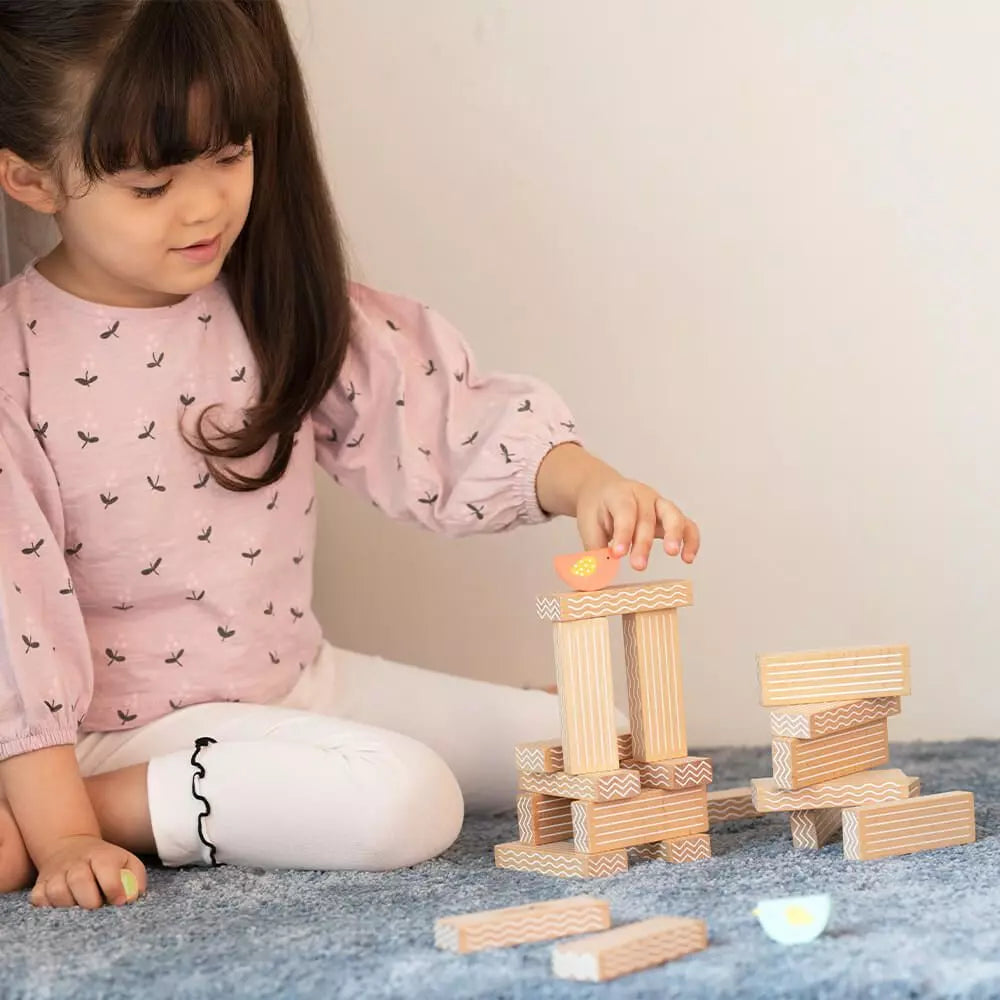Menina a brincar com o Classic World Jogo de empilhar pássaros, estimulando a criatividade e a coordenação.