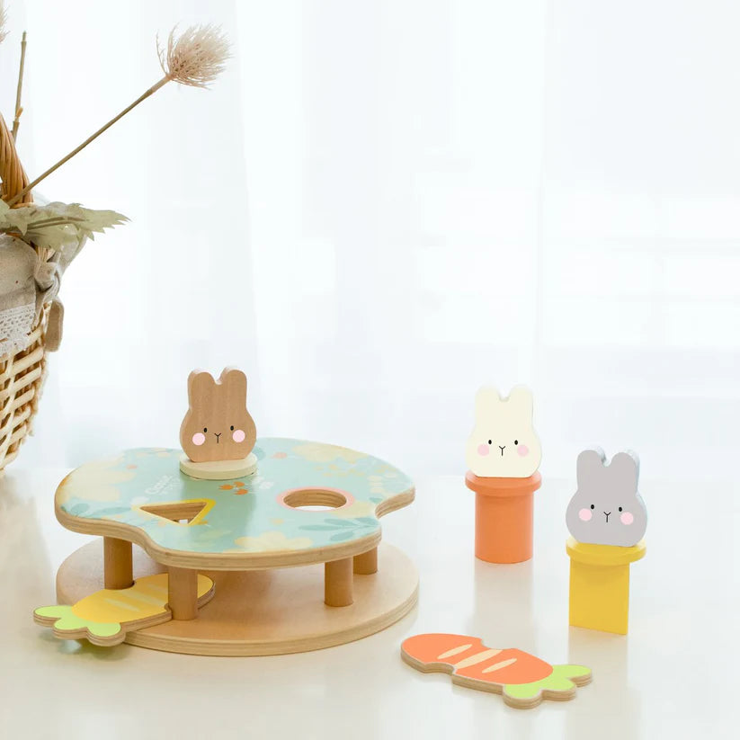 Jogo de encaixe dos Coelhos Classic World com três coelhinhos de madeira coloridos e cenouras, demonstrando um brinquedo educativo para bebês.