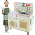 Criança sorridente com avental e colher, ao lado da cozinha de brincar Classic World Natural Kitchen.