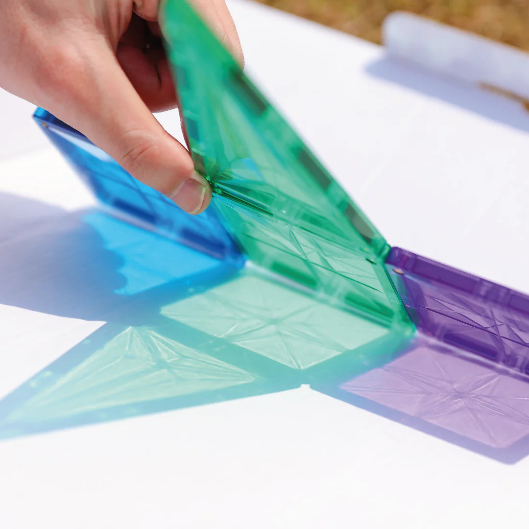 Mãos a montar um bloco magnético Clever Clixx Geo pastel, mostrando a interação e o processo de construção.