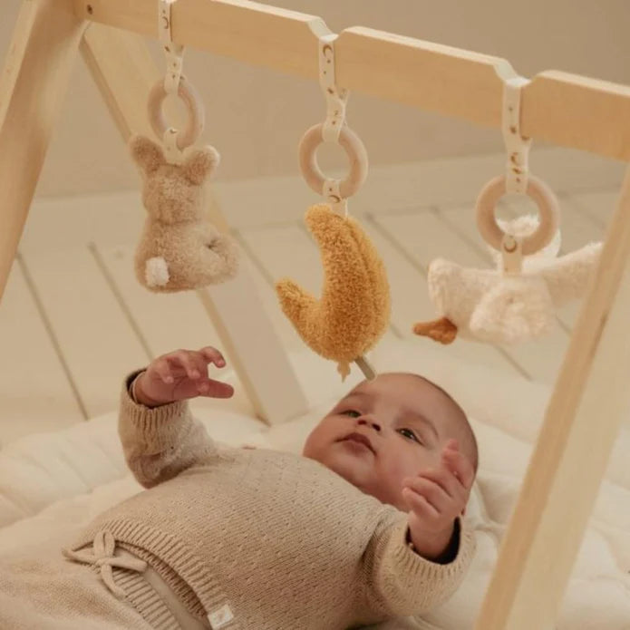 Close-up de um bebé a olhar para os brinquedos suspensos do ginásio de atividades Little Dutch, focando na interação entre o bebé e os objetos pendurados.