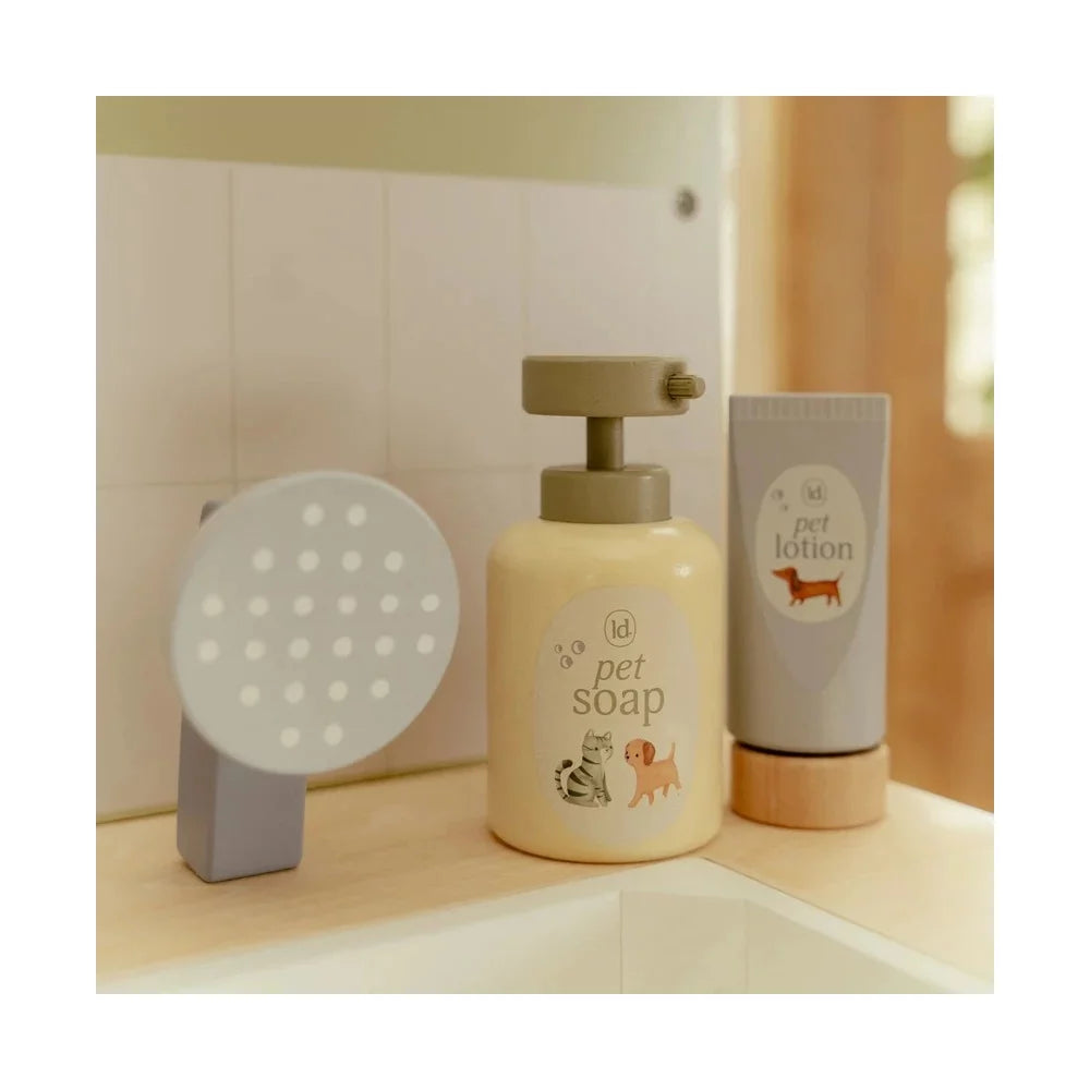 Close-up dos frascos de sabão para animais (pet soap) e loção (pet lotion) em madeira, junto ao chuveiro de brincar.