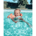 Criança a brincar na piscina usando o colete de flutuação Swim Essentials, com padrão de criaturas marinhas.