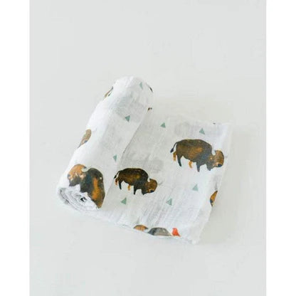 Muselina de algodão da Little Unicorn, dobrada, com padrão de bisontes castanhos e pequenos triângulos verdes sobre fundo branco.