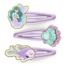 Três ganchos de cabelo de mola em tom lilás, decorados com uma sereia, um peixe e uma concha com pérola, todos com contorno dourado.