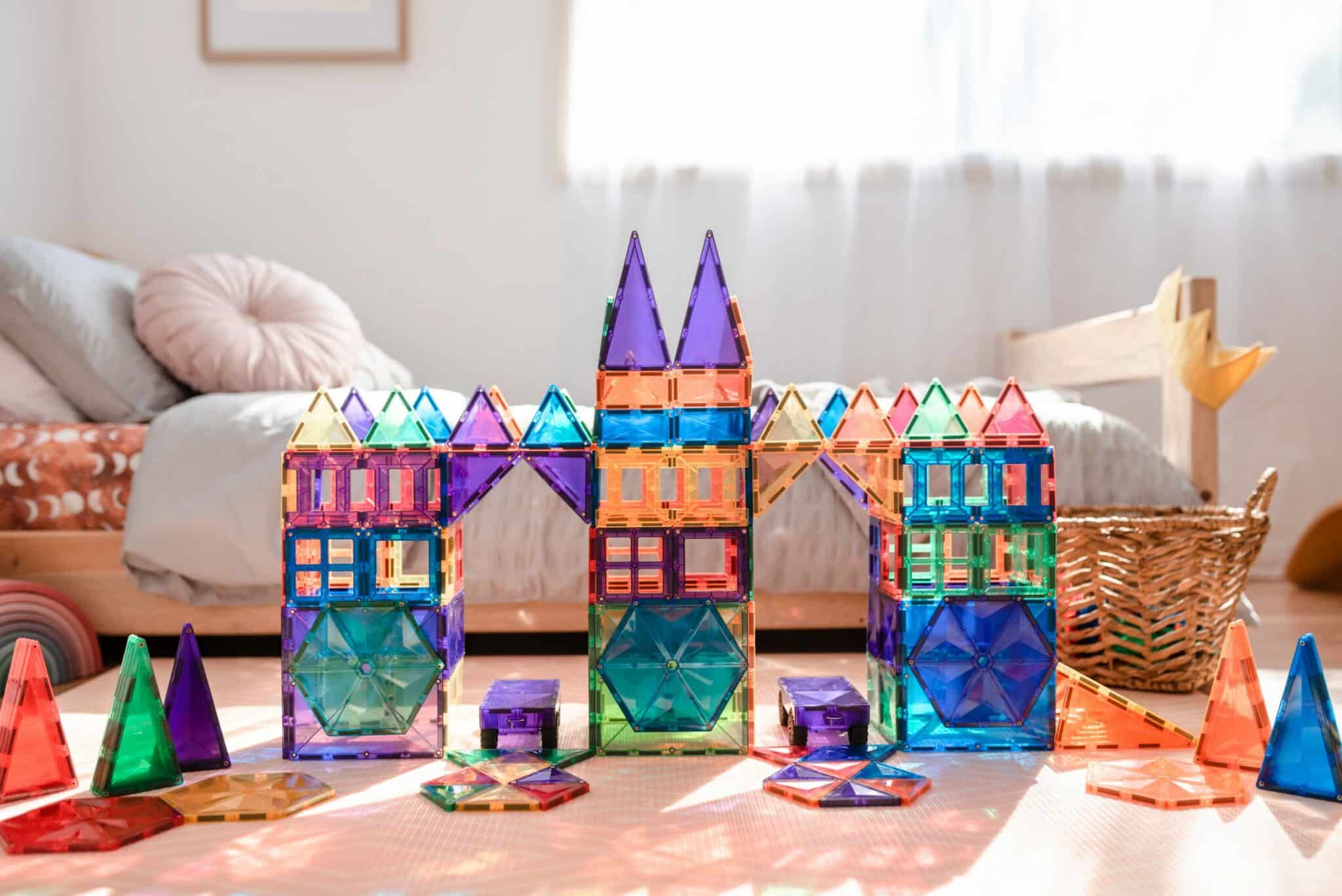 Grande castelo colorido construído com blocos magnéticos Connetix Rainbow num quarto.
