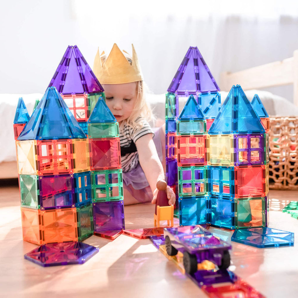 Criança brincando com um castelo grande construído com blocos magnéticos Connetix Rainbow Mega Pack.