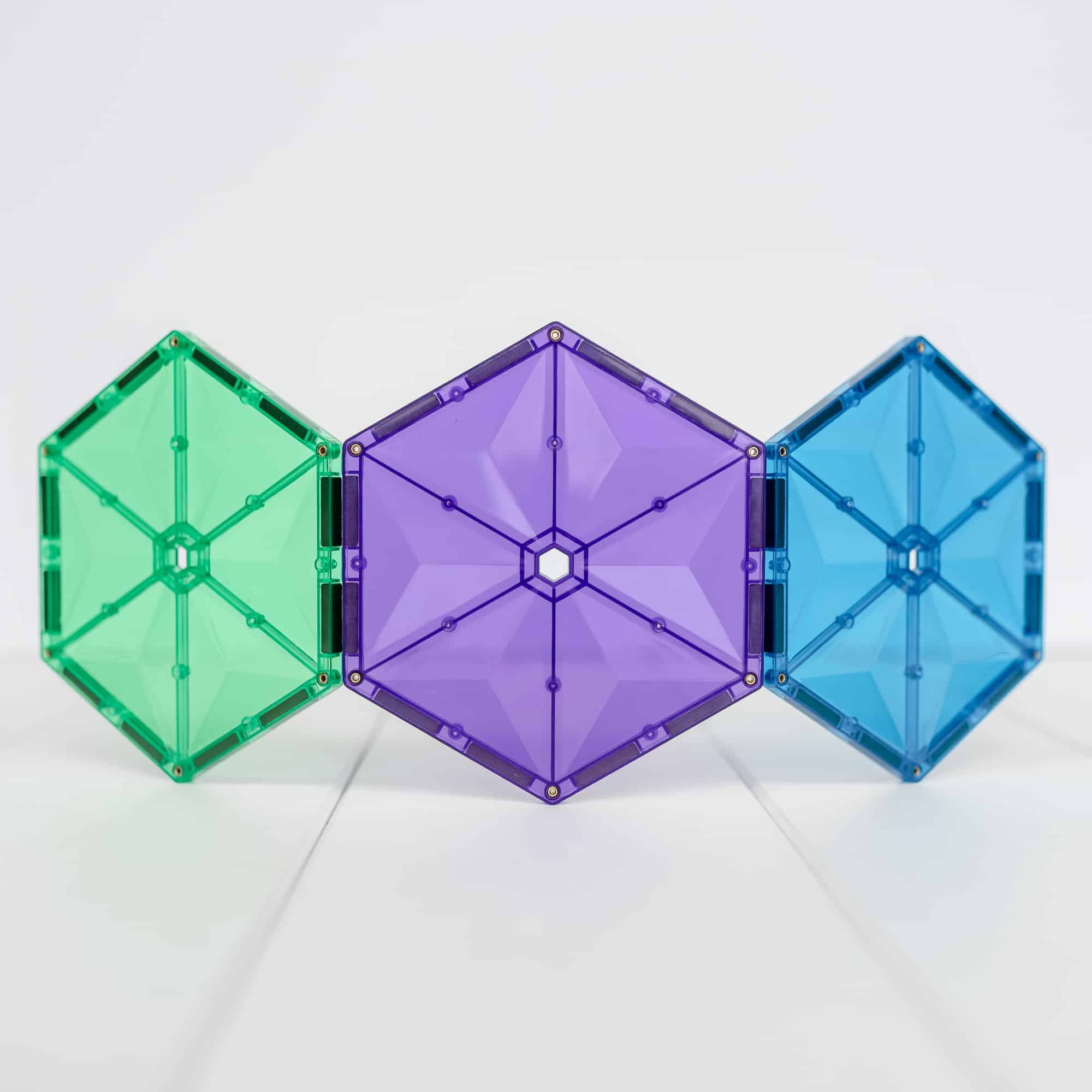 Três hexágonos grandes coloridos (verde, roxo, azul) de blocos magnéticos Connetix.