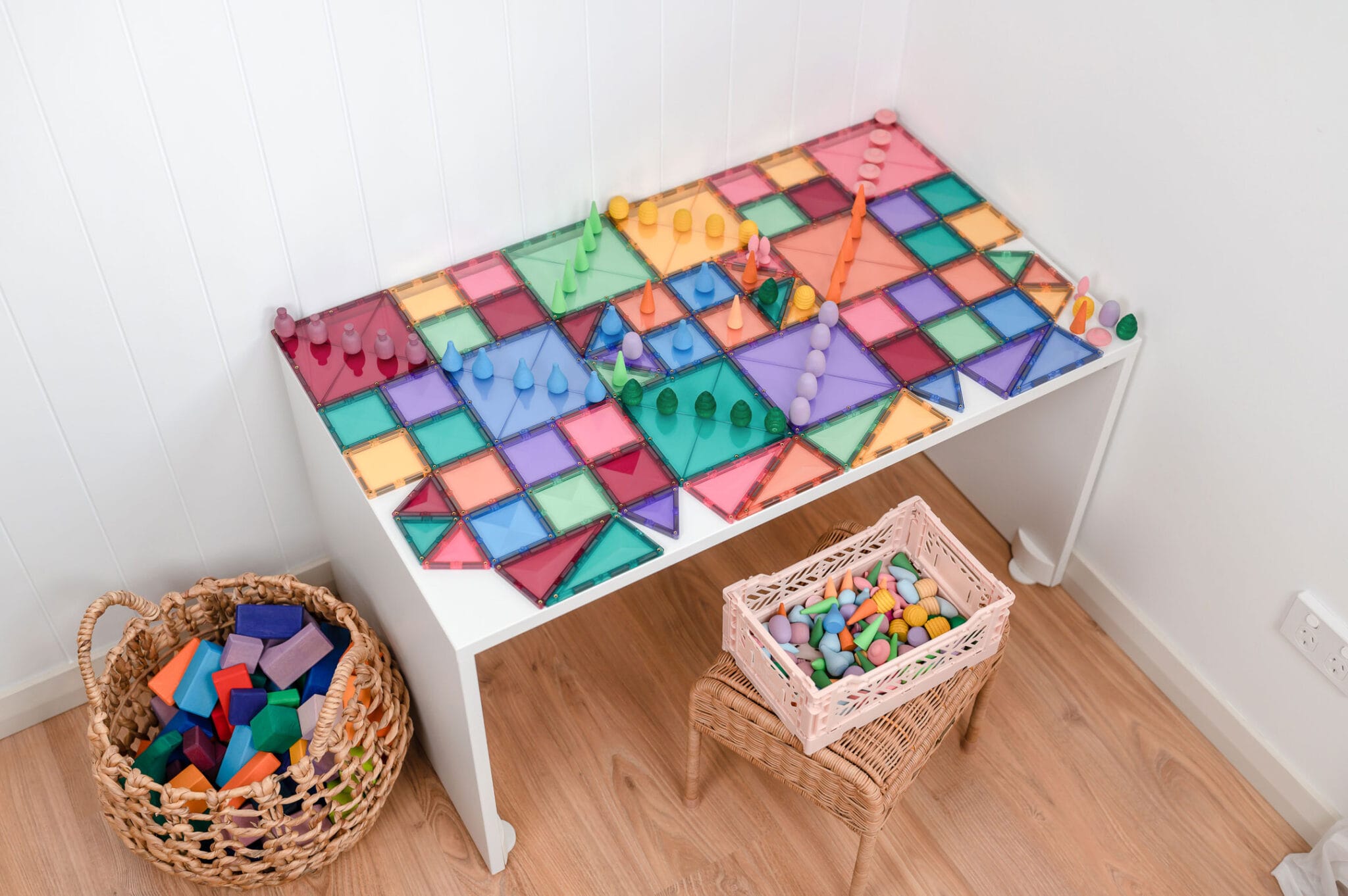 Mesa com uma grande construção colorida feita com os blocos Connetix Pastel e outras peças de jogo.