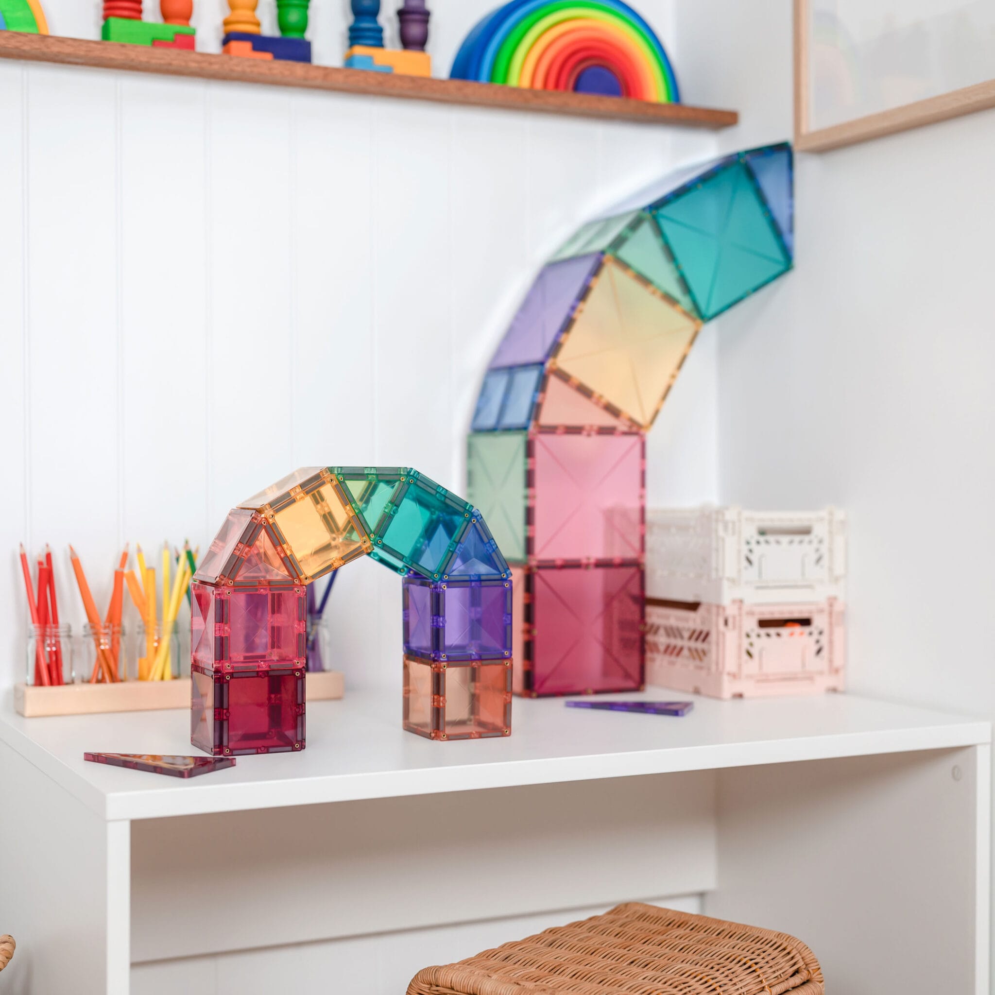Construções coloridas feitas com blocos Connetix Pastel, incluindo um túnel e um arco, em cima de uma secretária.