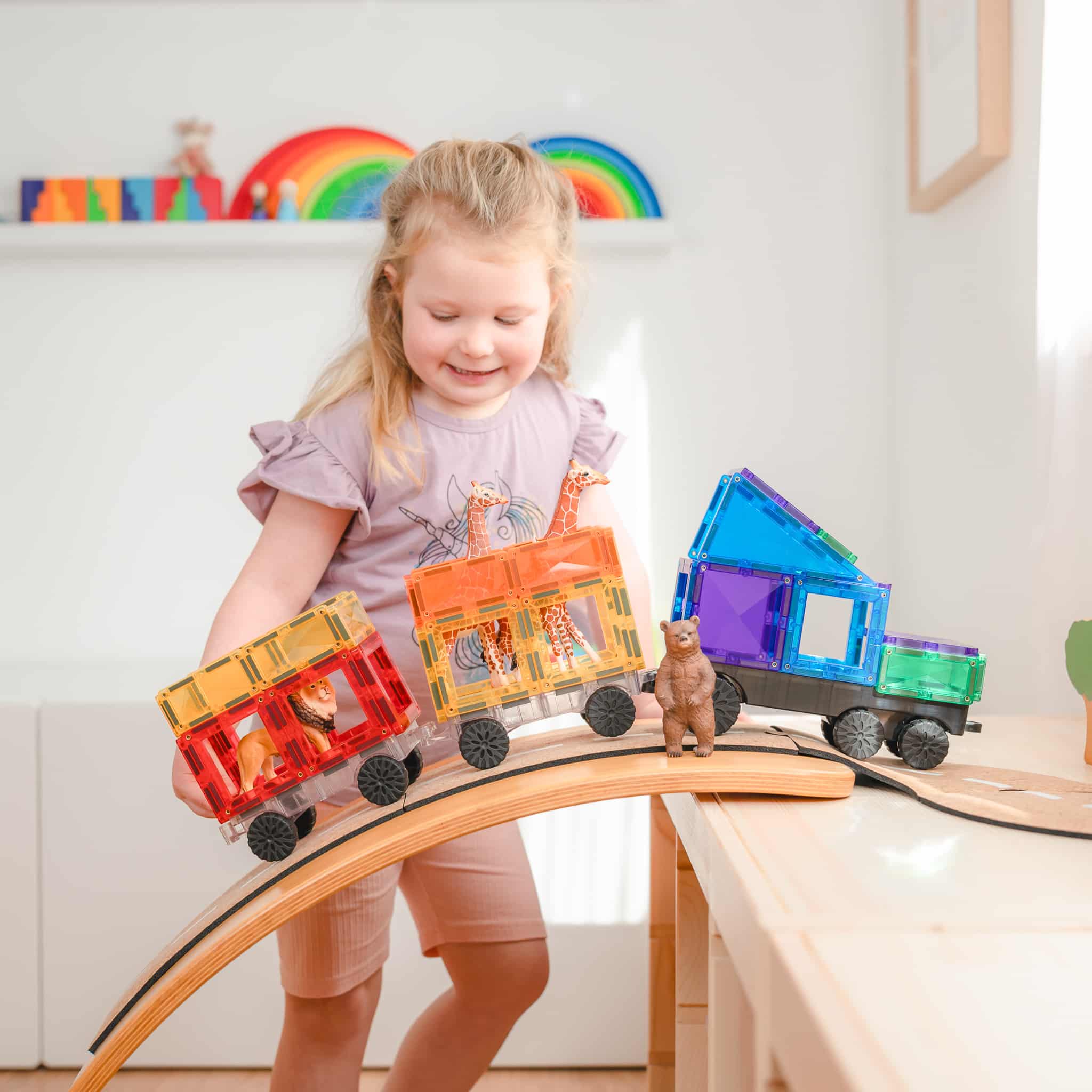 Criança a brincar com veículos construídos com o set Connetix Rainbow Transport 50 pc.