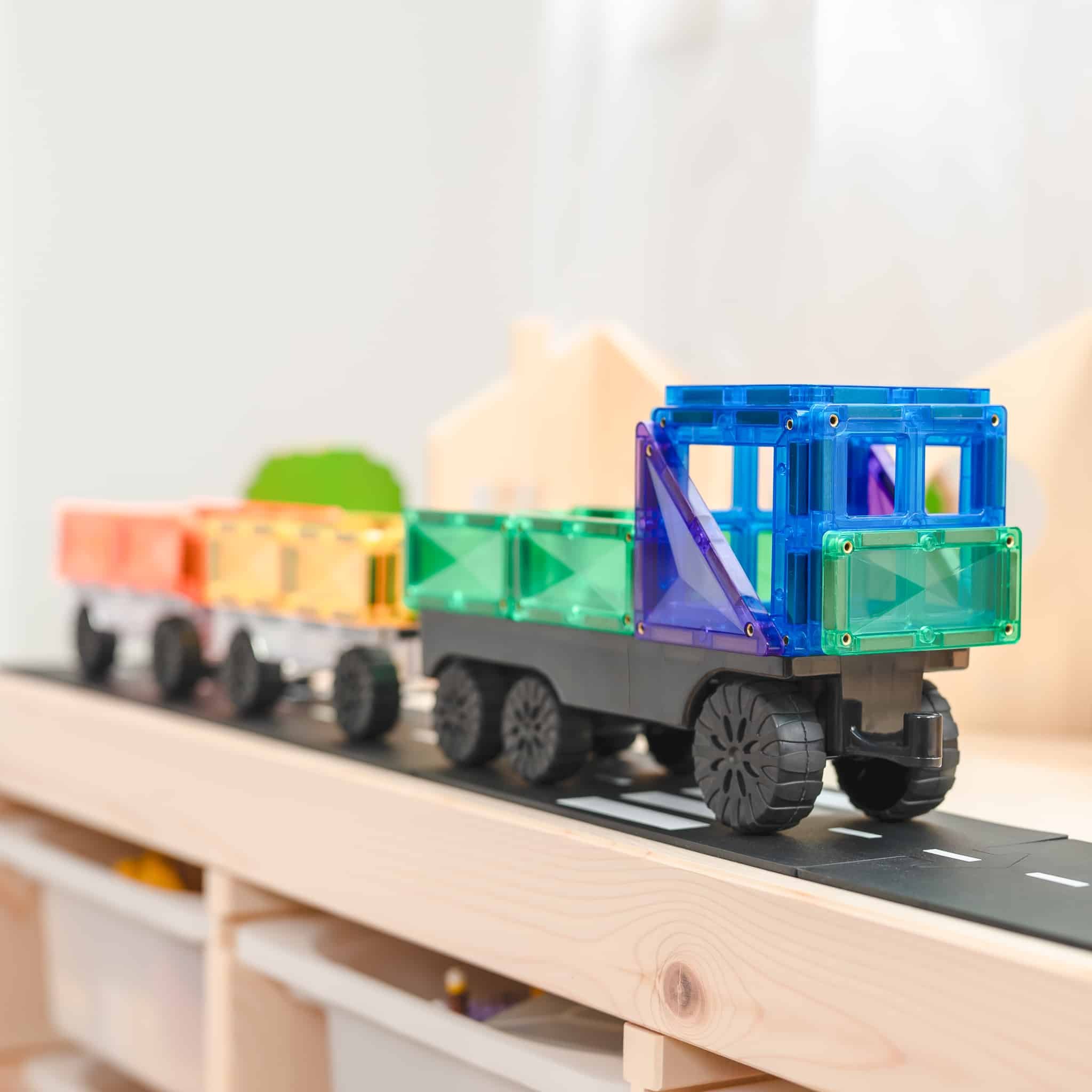 Comboio construído com blocos Connetix Rainbow Transport 50 pc numa superfície de madeira.