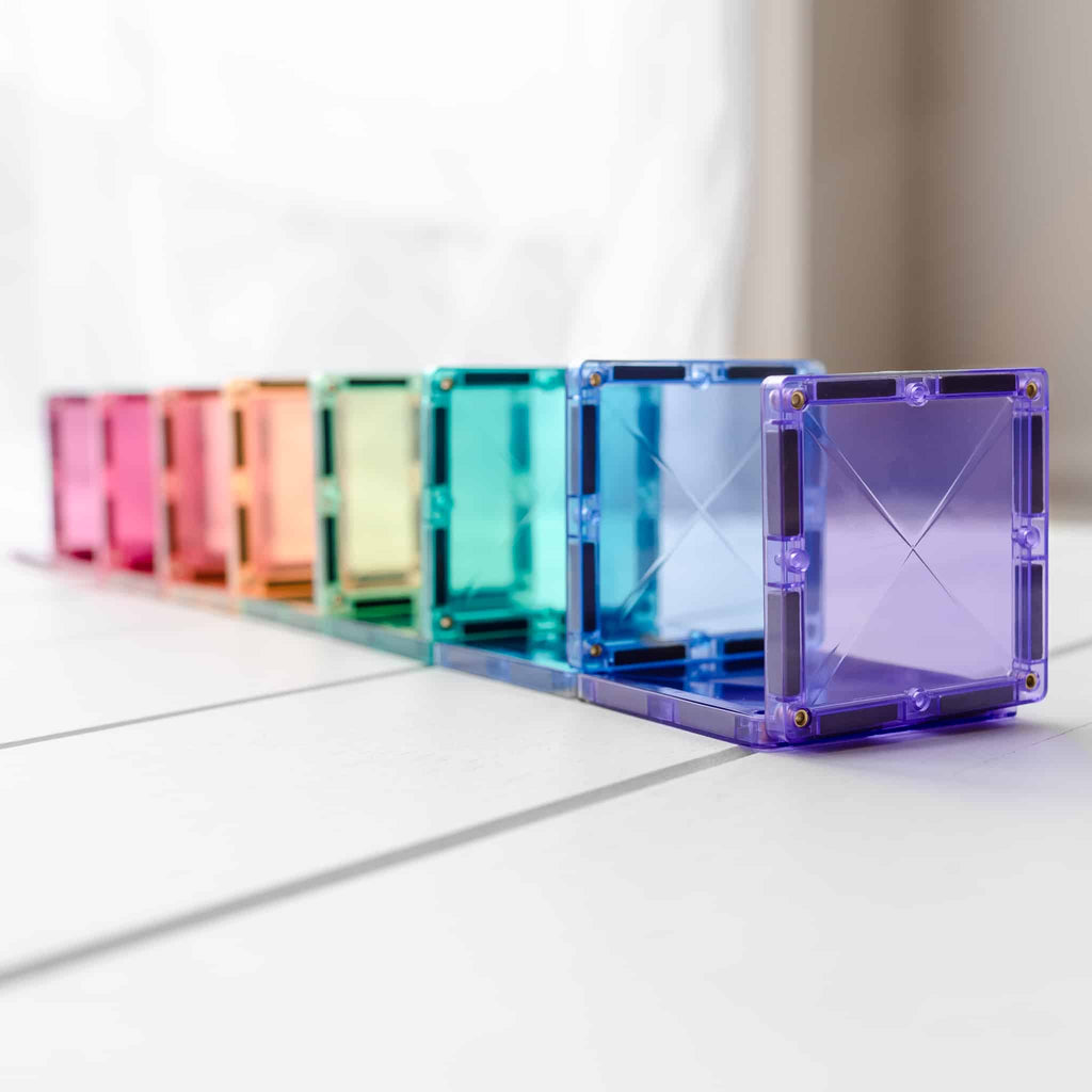 Fila de blocos magnéticos quadrados Connetix transparentes em cores pastel, alinhados horizontalmente, mostrando a profundidade e a construção 3D.
