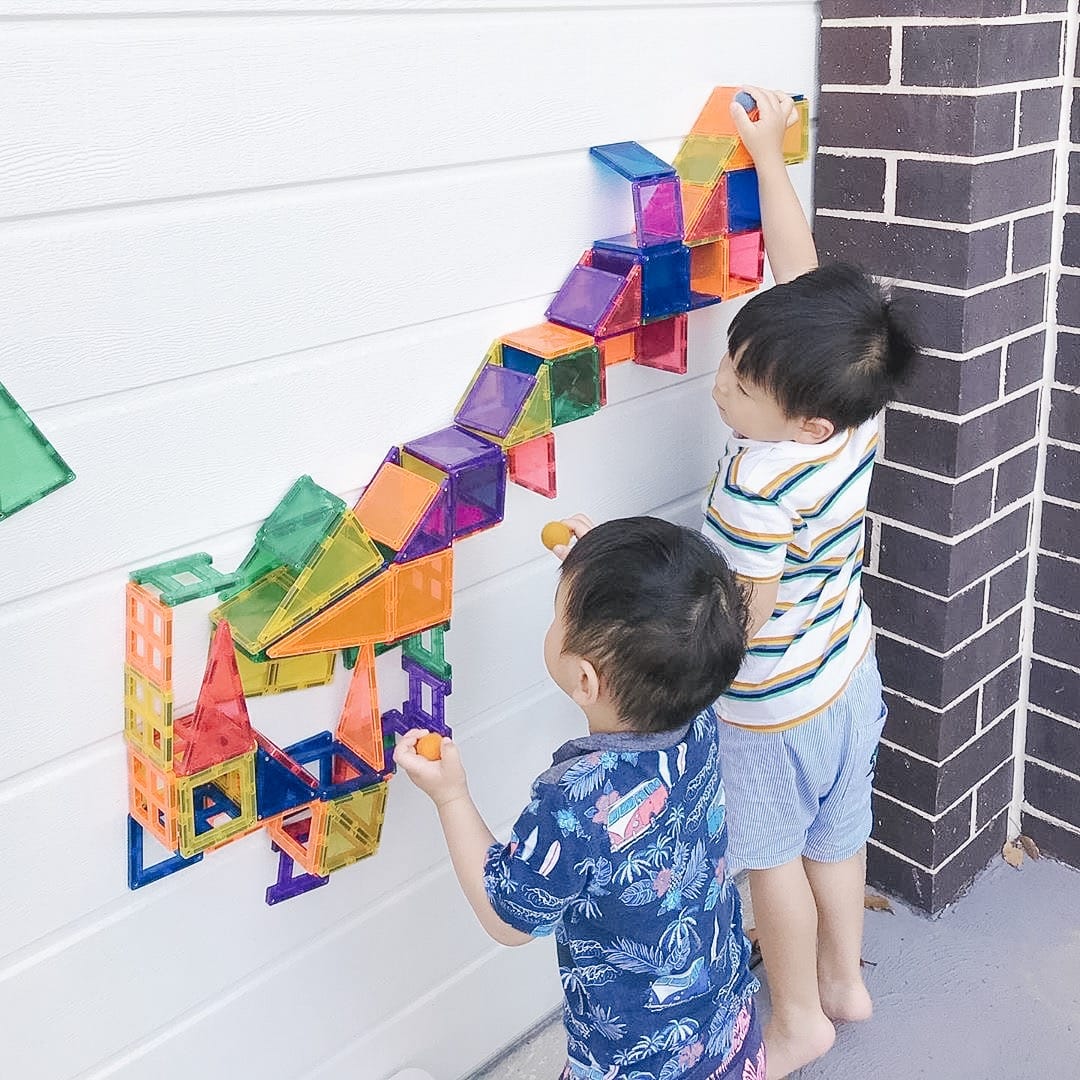 Duas crianças a construir na parede com blocos magnéticos Connetix Rainbow Creative 102 pc.