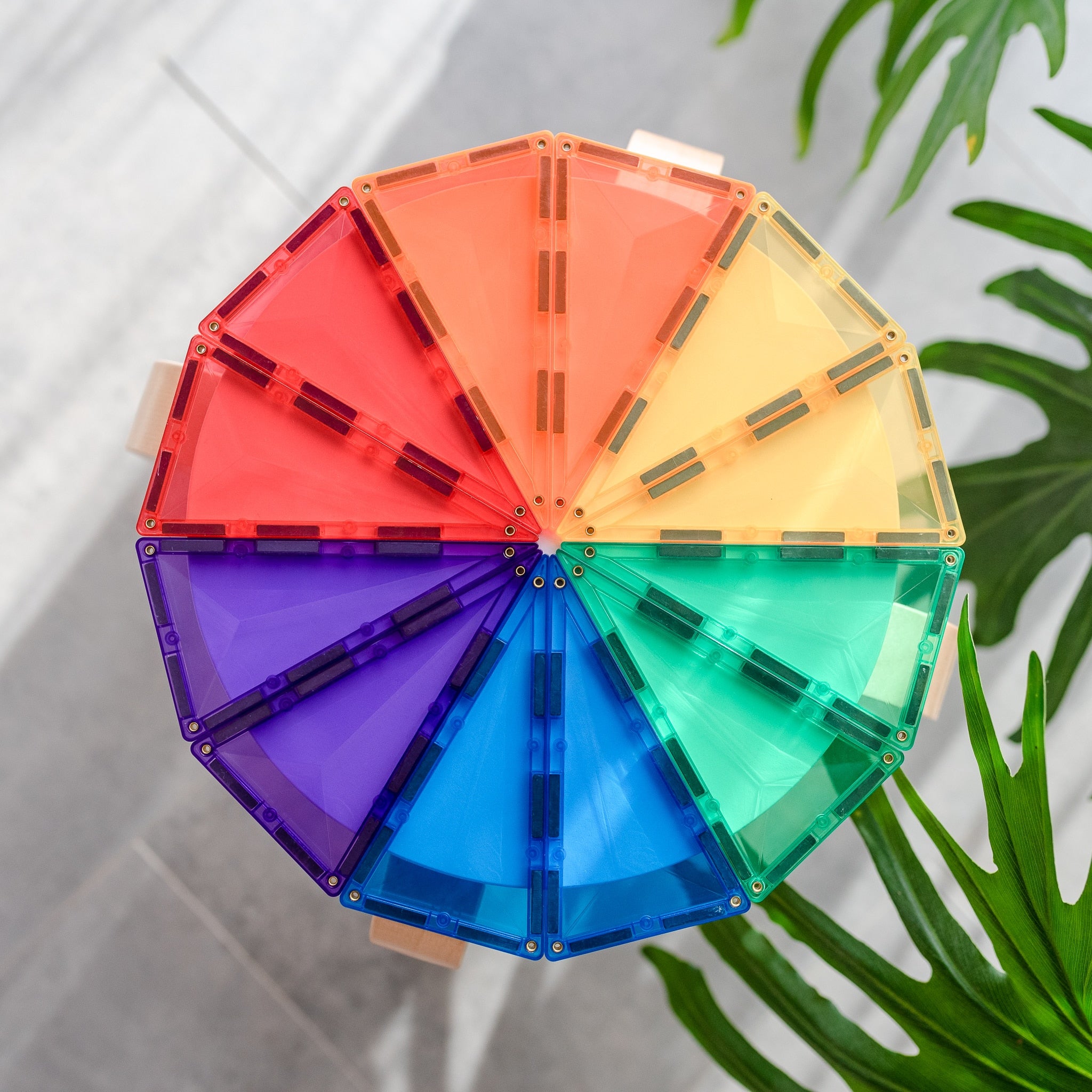 Construção circular colorida feita com blocos magnéticos Connetix Rainbow Geometry em cima de uma mesa.