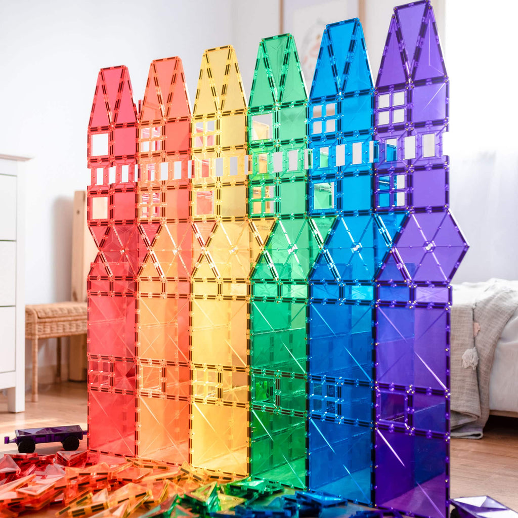 Sete torres altas em forma de casa, dispostas em sequência de cores do arco-íris, construídas com blocos magnéticos transparentes Connetix.