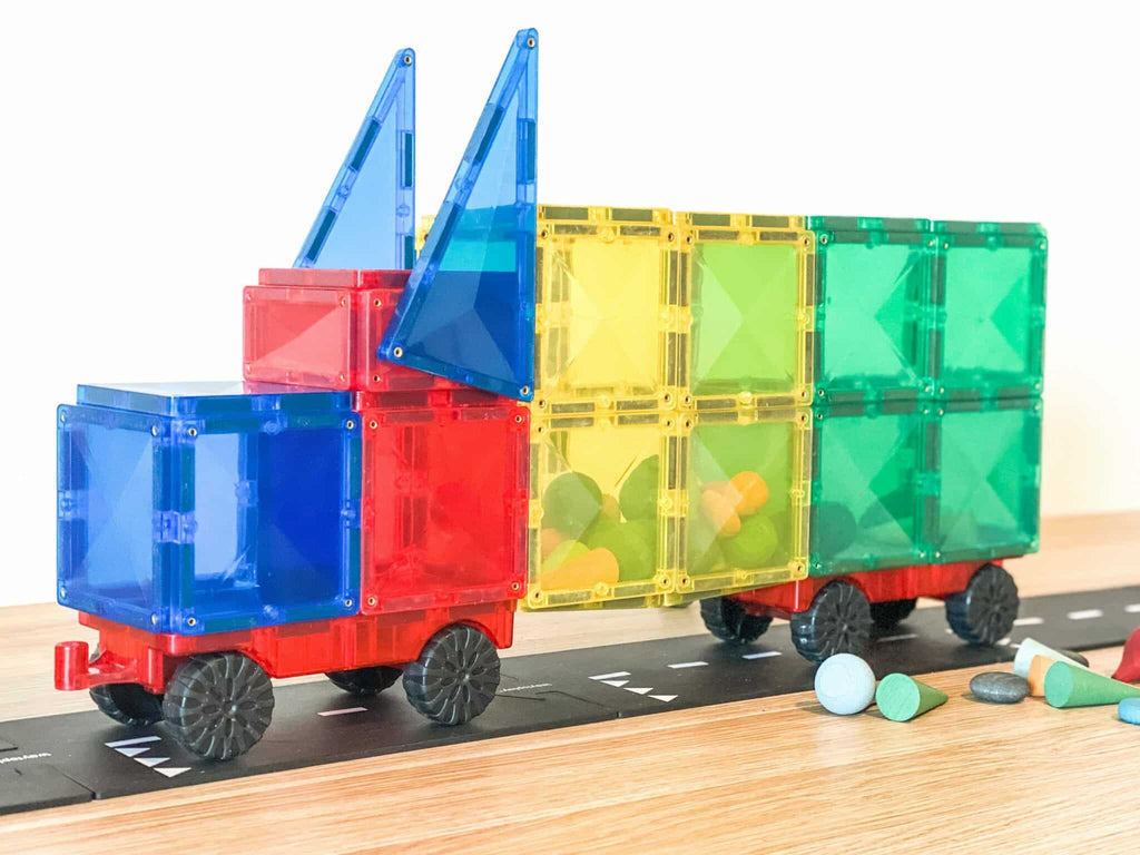 Camion de brincar Connetix Rainbow Motion (24 peças) montado com blocos magnéticos coloridos, exibindo as bases com rodas.