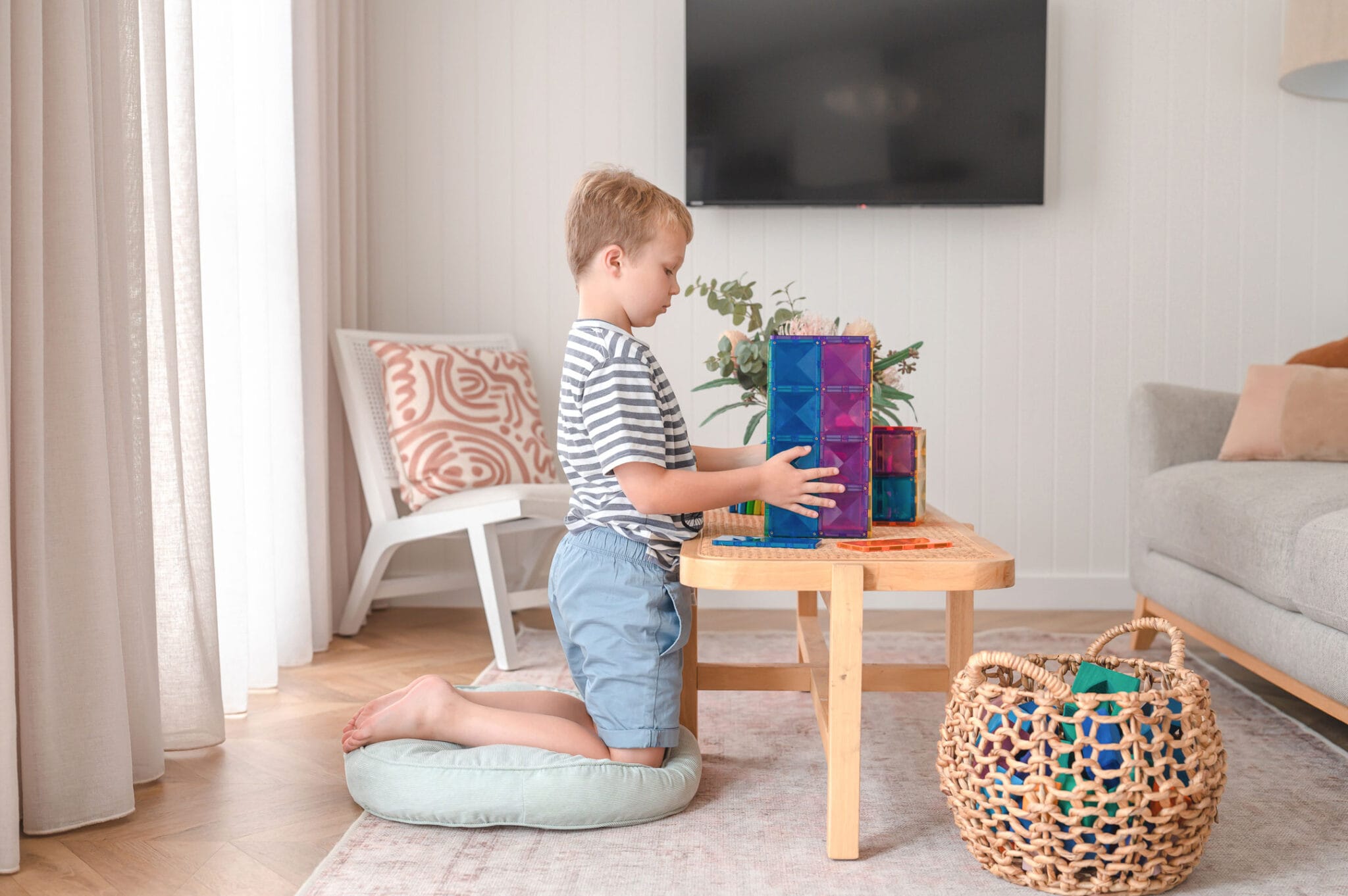 Menino a construir uma estrutura com os blocos magnéticos Connetix Rainbow Rectangle, mostrando a capacidade de construção e design do brinquedo.