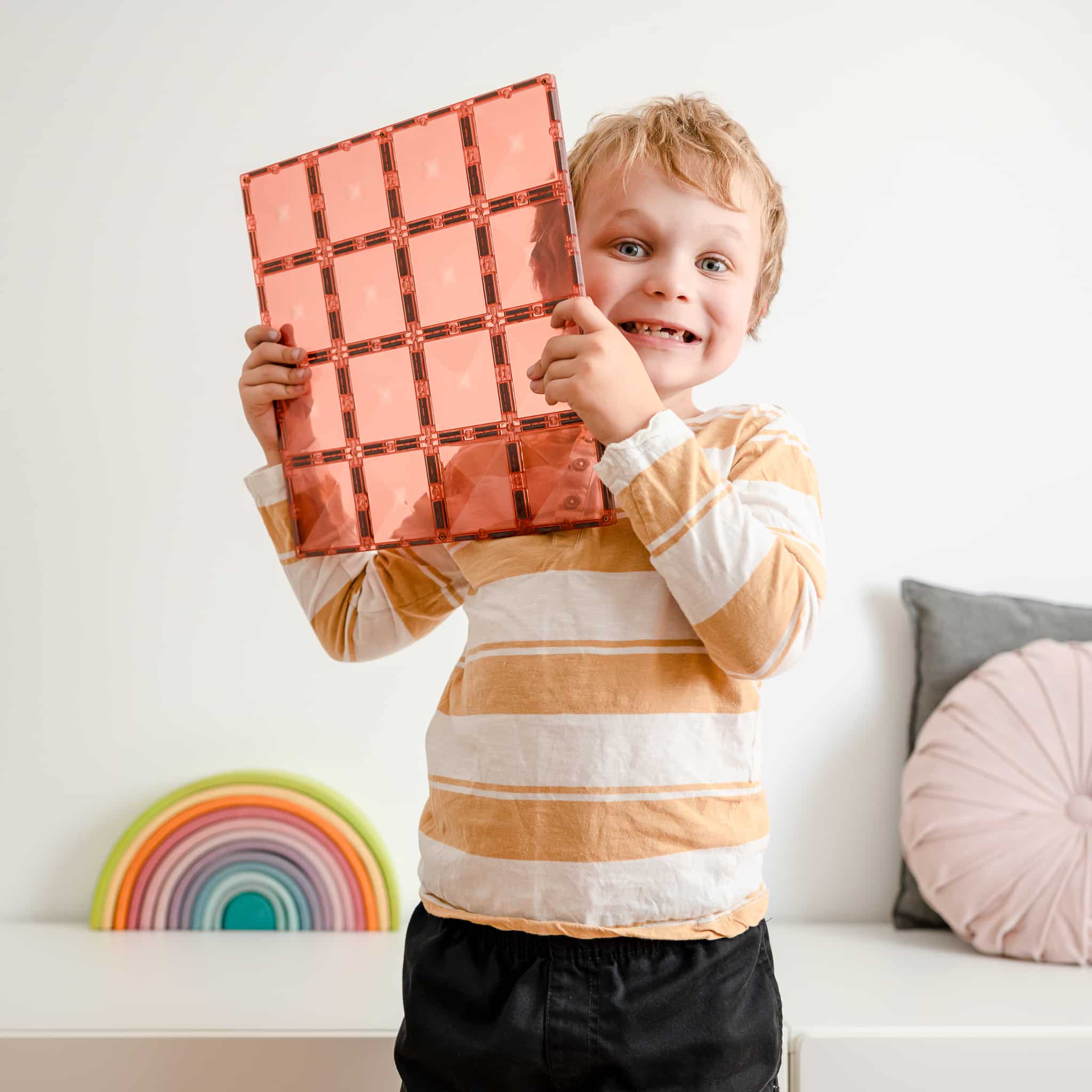 Criança sorrindo segurando uma base magnética Connetix Peach. Brinquedo educativo e divertido para crianças.