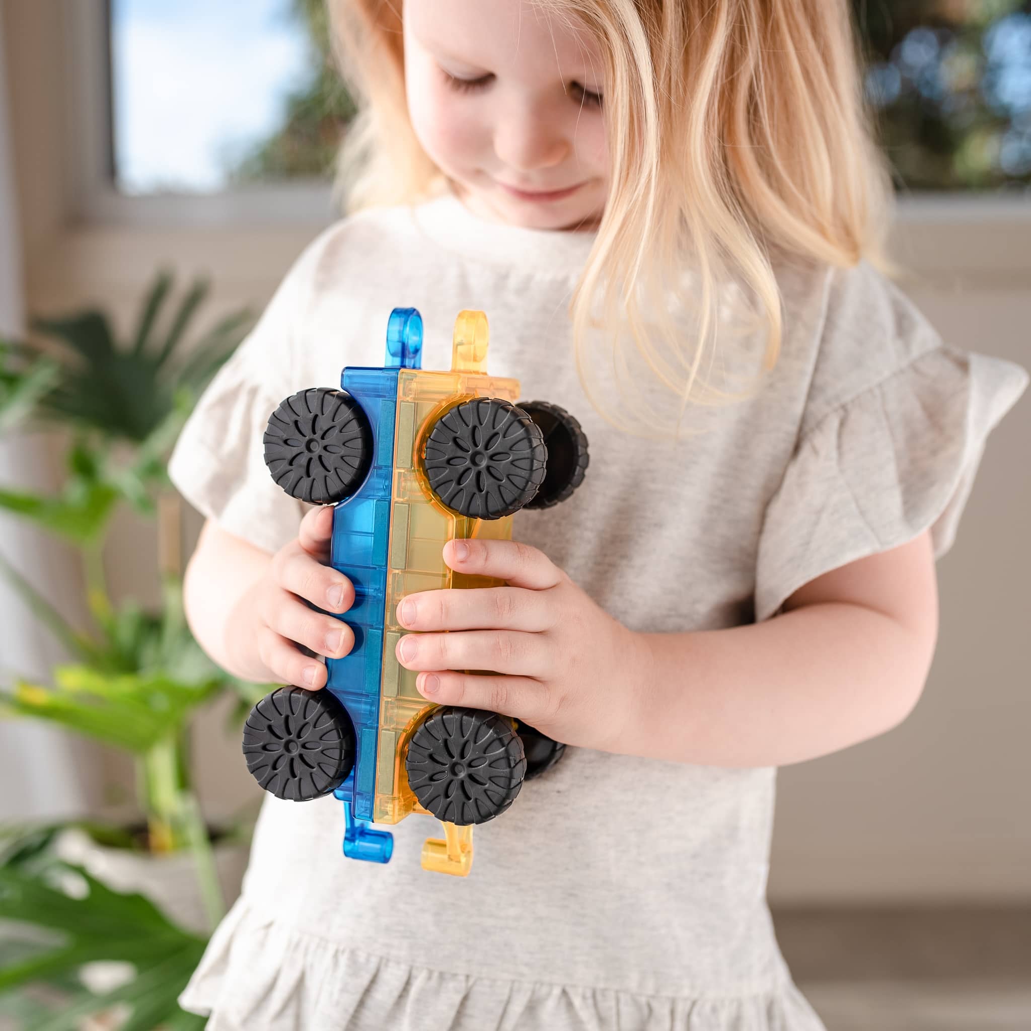 Menina brincando com os carros magnéticos Connetix 2 Piece Transport Car. Brinquedo educativo.