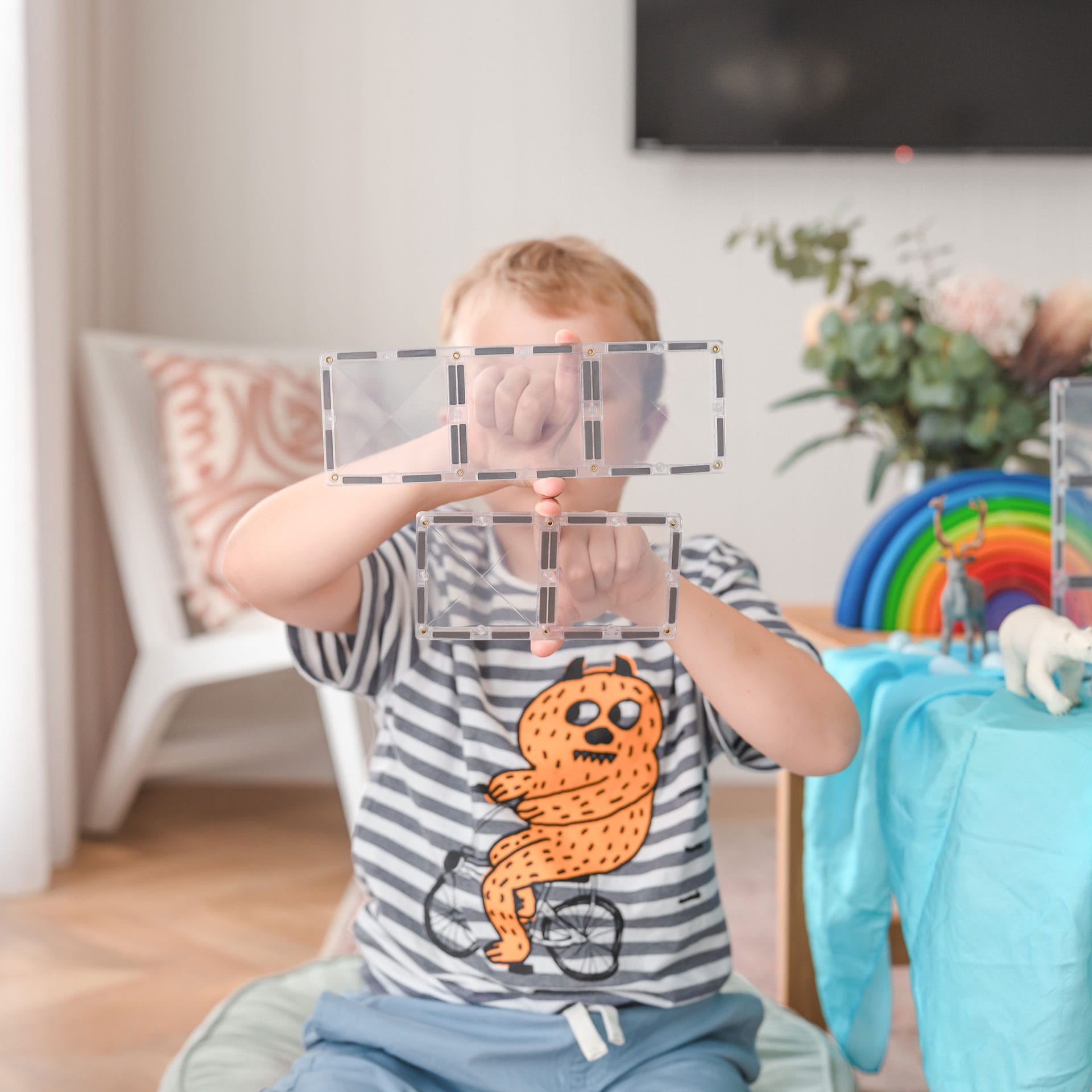 Detalhe de criança a segurar blocos magnéticos Connetix Clear Rectangle conectados.