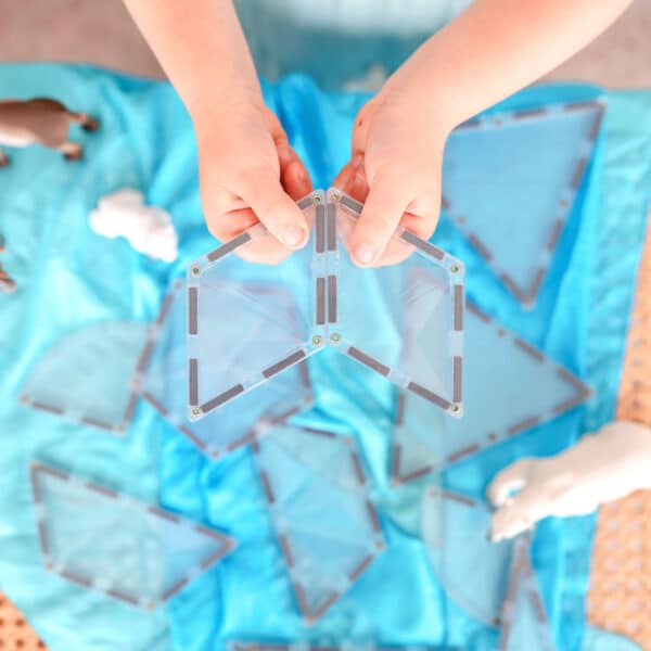 Mãos de criança a conectar blocos magnéticos transparentes Connetix Clear Shape Expansão 24 pc.