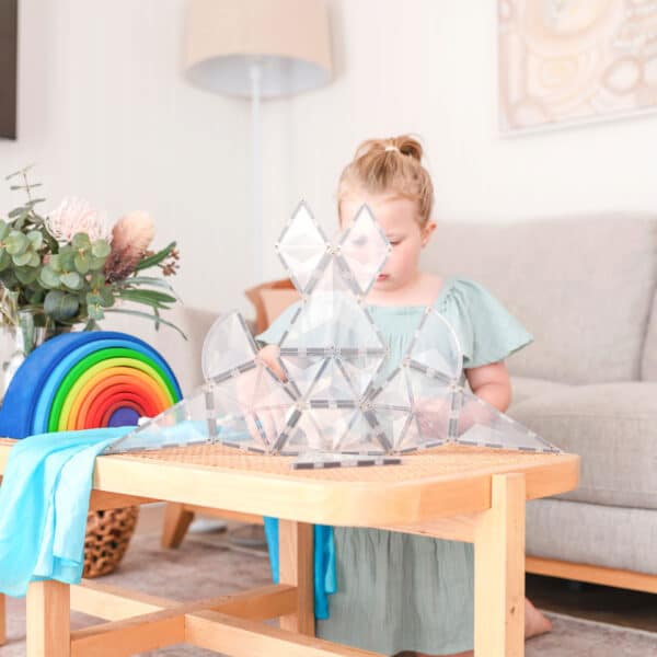 Criança a brincar com estrutura feita com Connetix Jogo blocos Magnético Clear Shape Expansão 24 pc em mesa.