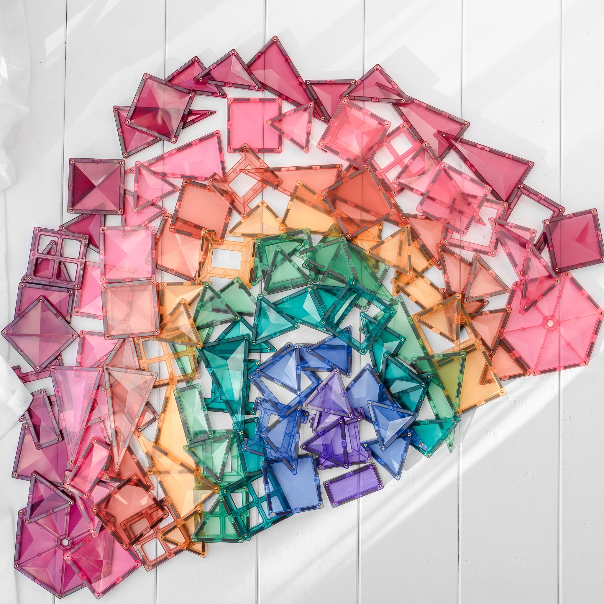 Grande coleção de blocos magnéticos Connetix Pastel de várias formas espalhados.