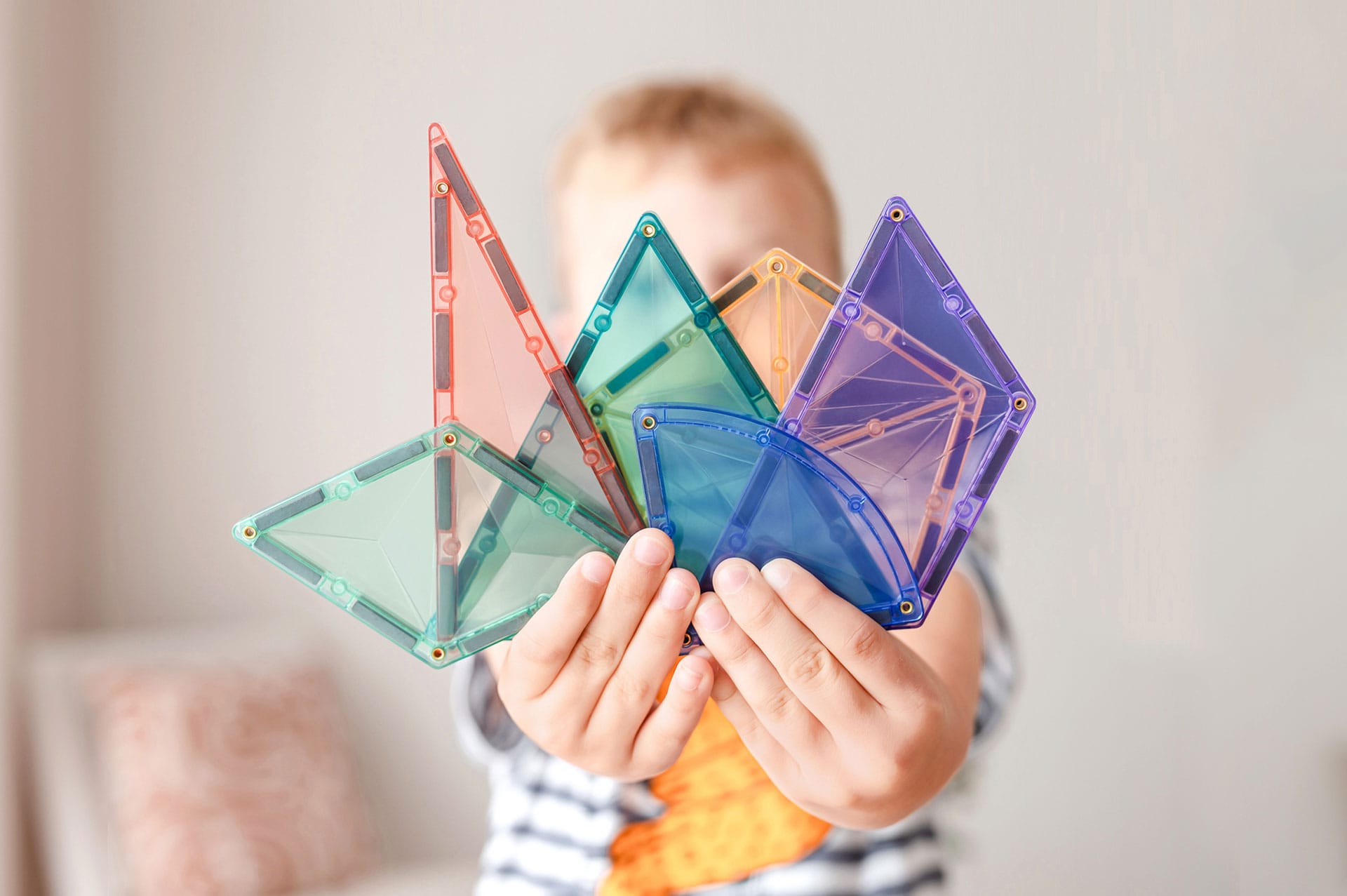 Mãos de criança segurando vários blocos magnéticos Connetix Pastel Shape Expansion Pack.