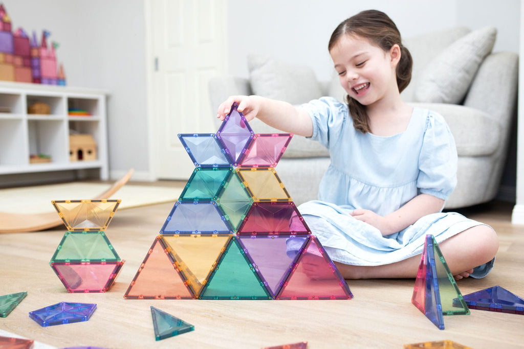 Menina adicionando um bloco magnético Connetix Pastel Shape Expansion Pack a uma construção.