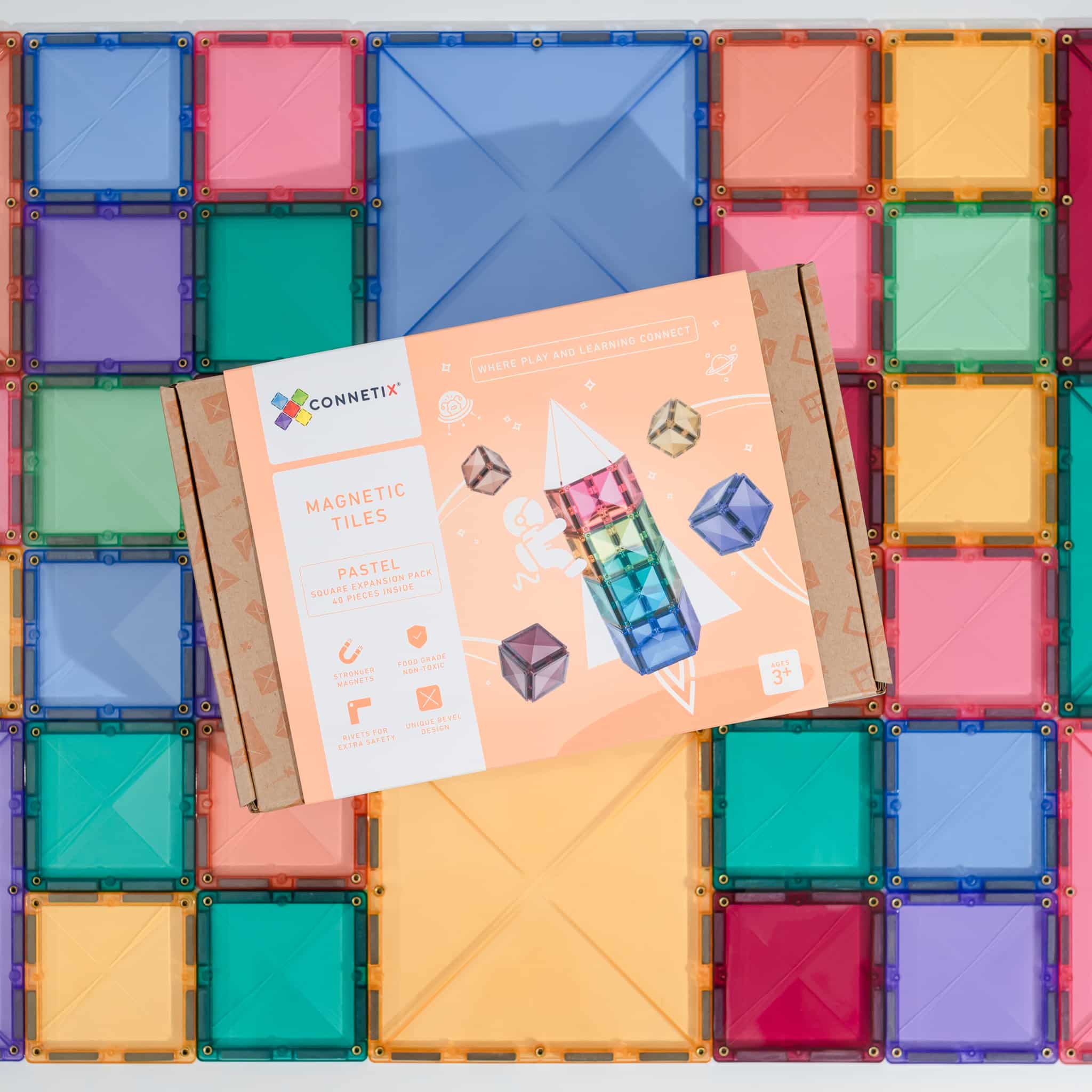 Caixa Connetix Pastel Square 40 pc sobre fundo de blocos magnéticos pastel coloridos.