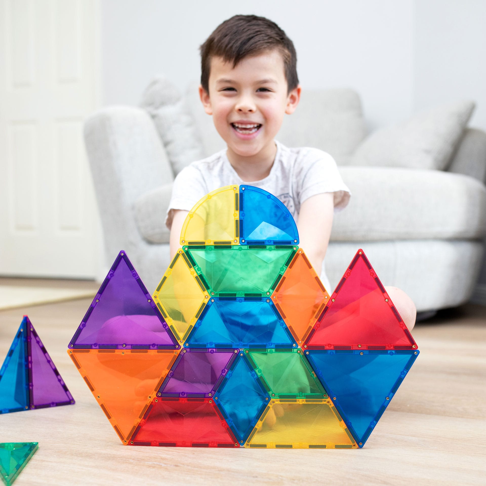 Criança feliz com uma grande estrutura colorida construída com blocos magnéticos Connetix 36 pc expansion.