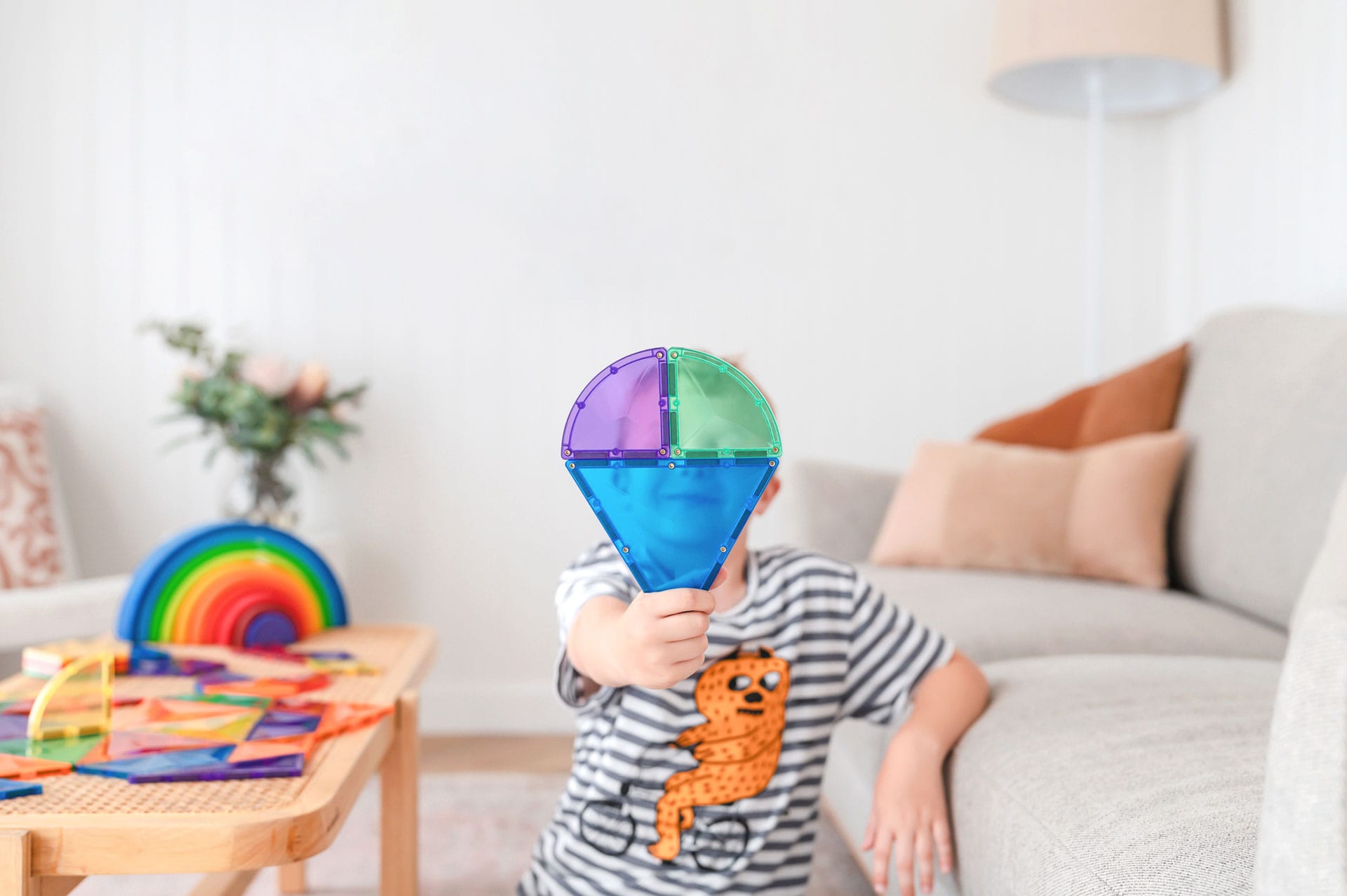 Criança sorridente segura uma criação de blocos magnéticos Connetix do conjunto Rainbow Shape Expansion 36 pc.