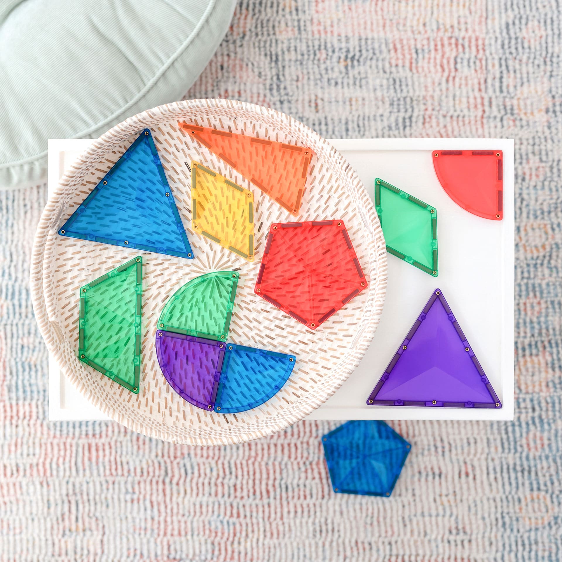 Vista aérea das diferentes formas do conjunto Connetix Rainbow Shape Expansion 36 pc numa cesta e mesa.
