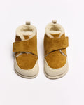 Par de botas de bebé estilo barefoot Coucouçava em pele nobuck amarelo mostarda com forro de pelo, fecho velcro e sola clara.