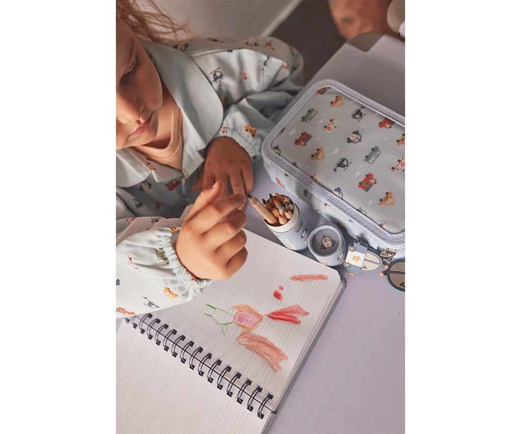 Criança a desenhar com lápis de cor, vestindo um babete com mangas impermeável Tutete, mostrando o uso prático.