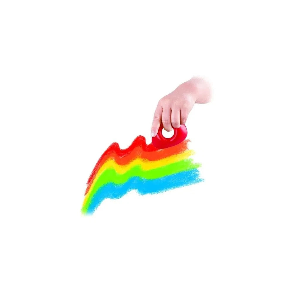 Mão de uma criança a utilizar um lápis de cera ergonómico vermelho para desenhar linhas coloridas num papel.