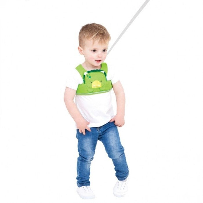 Criança pequena a usar o arnês Trunki ToddlePak verde, a caminhar com a fita de segurança suspensa acima.