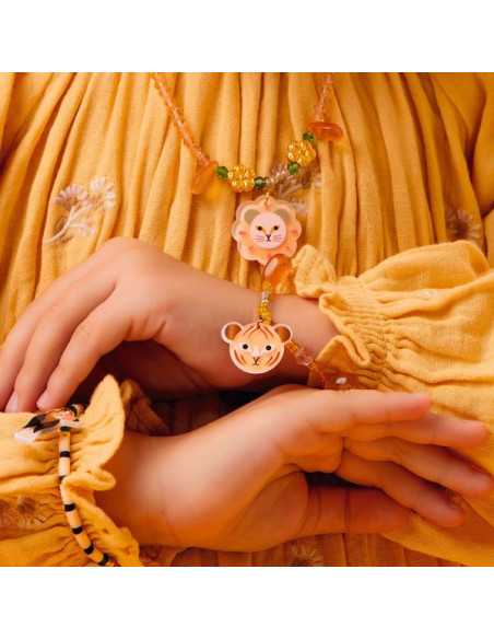 Criança com pele clara a usar uma pulseira amarela e rosa com pendente de tigre, sobre uma roupa amarela.