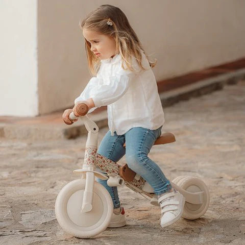 Criança pequena a utilizar o triciclo Little Dutch na configuração de bicicleta de equilíbrio, sorridente e concentrada.