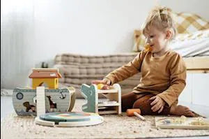 Criança brincando com o jogo de martelar e xilofone small foot, mostrando a interação e a diversão.