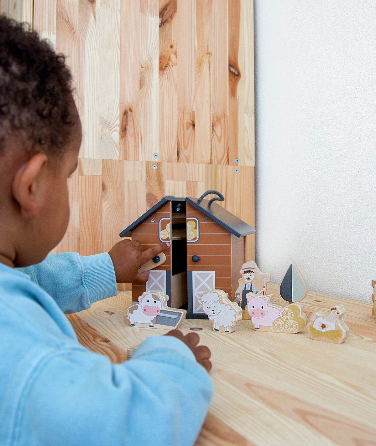 Criança a brincar com a quinta dobrável Tryco, interagindo com os animais e acessórios. Brinquedo divertido e educativo.