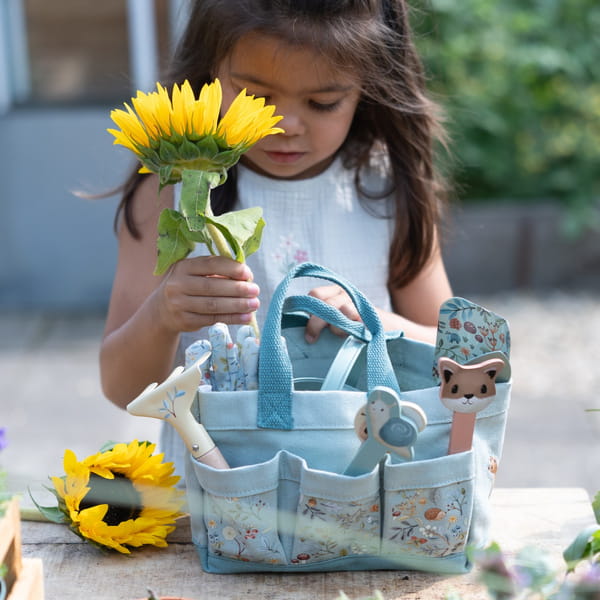 Criança a segurar um girassol, com o conjunto de jardinagem Forest Friends da Little Dutch em primeiro plano.