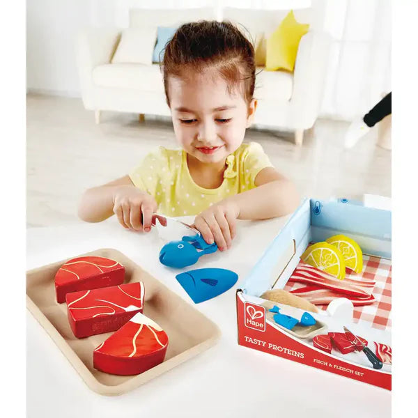 Criança a cortar peixe de madeira com faca de brinquedo Hape