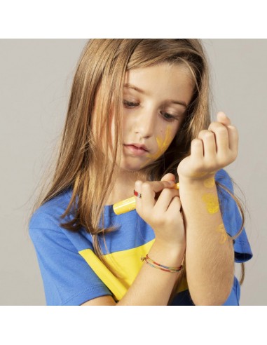 Menina a utilizar um marcador Nailmatic amarelo para desenhar uma tatuagem temporária no pulso.