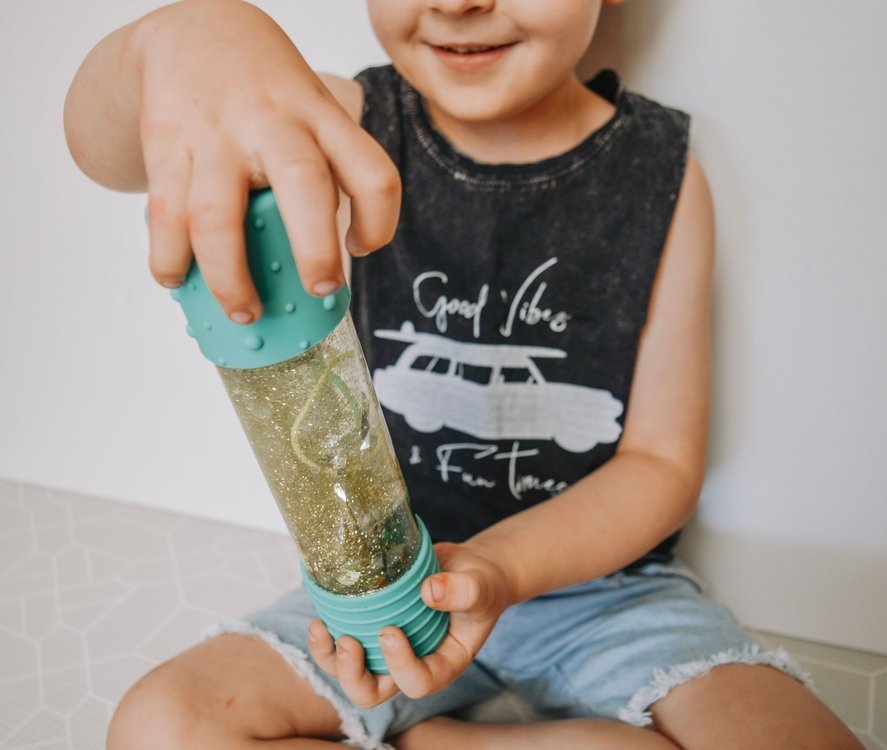 Criança a mostrar a Jellystone DIY Garrafa da Calma com o conteúdo misturado.