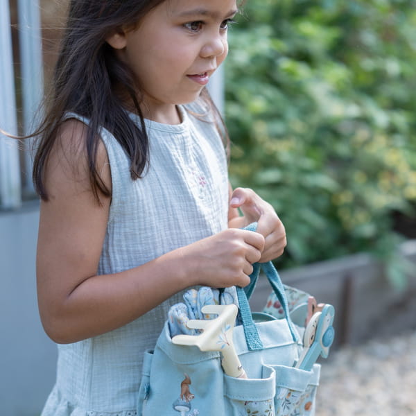 Detalhe de uma criança a segurar a bolsa de jardinagem da Little Dutch com ferramentas no interior.