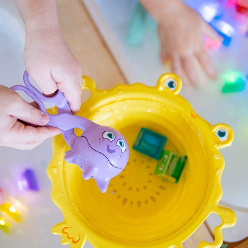 Criança a usar o filtro GloPals numa mesa sensorial com água e cubos luminosos, explorando texturas e movimentos.