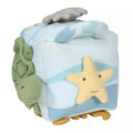 Cubo de atividades sensorial Tikiri Oceano com uma tartaruga verde saliente num lado e uma estrela do mar amarela com rosto bordado no outro. O fundo tem padrões de ondas azuis.
