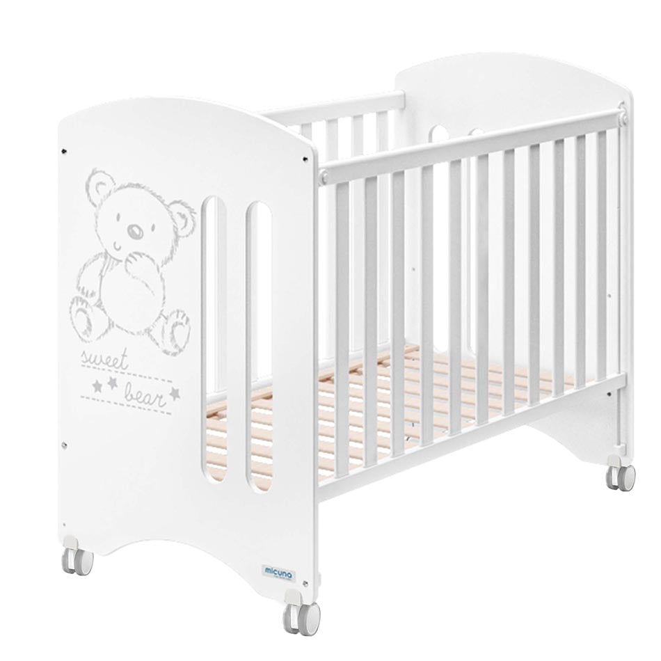 Mãe a colocar bebé no berço Micuna Sweet Bear 120x60 branco, com design de urso, em quarto infantil luminoso.